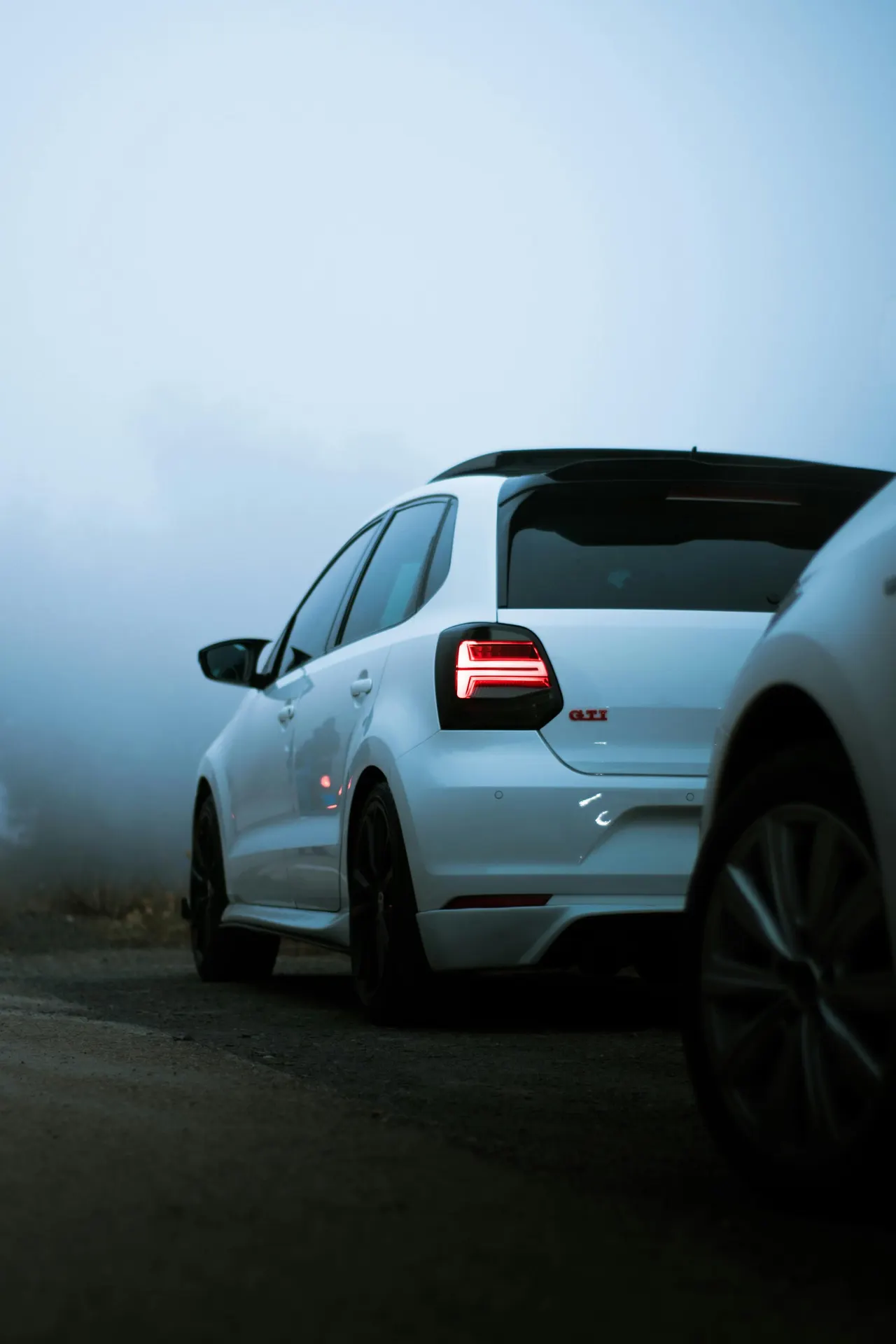 سيارة Volkswagen Polo GTI بيضاء، وهي سيارة مدمجة من مجموعة Volkswagen، متوقفة على طريق يكسوه الضباب